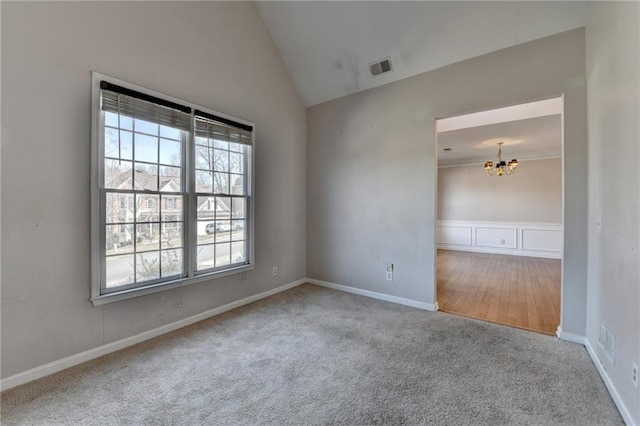 empty room featuring lofted ceiling, visible vents, carpet flooring, a chandelier, and baseboards