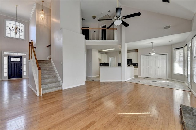 unfurnished living room with light wood finished floors, baseboards, stairs, and visible vents