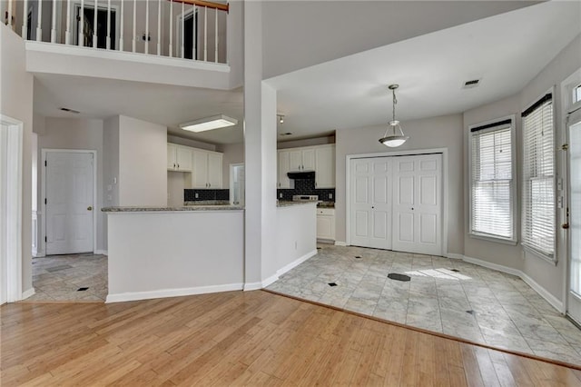 kitchen with visible vents, baseboards, light wood-style flooring, under cabinet range hood, and white cabinetry