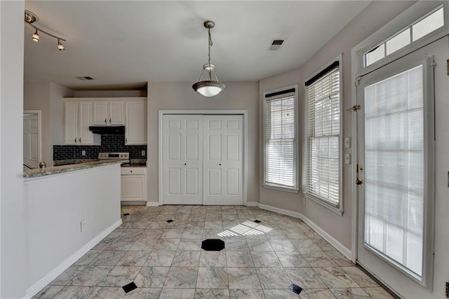 kitchen with under cabinet range hood, white cabinetry, visible vents, hanging light fixtures, and decorative backsplash