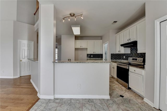 kitchen featuring stone countertops, under cabinet range hood, visible vents, stainless steel electric range, and backsplash