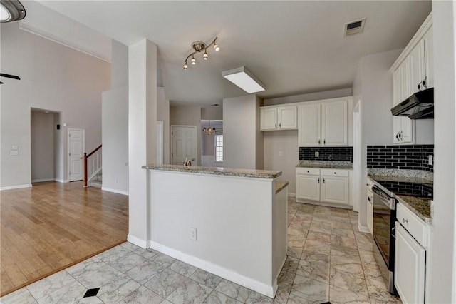 kitchen with electric range, visible vents, marble finish floor, stone counters, and under cabinet range hood