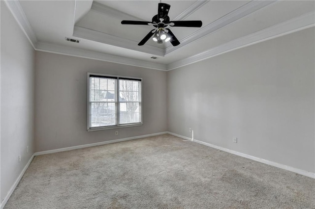 carpeted empty room with baseboards, a raised ceiling, visible vents, and crown molding