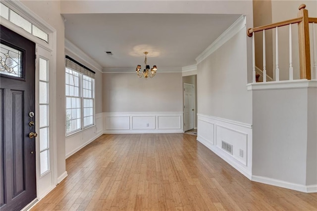 foyer entrance featuring a chandelier, ornamental molding, light wood-type flooring, and visible vents