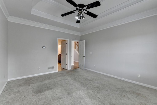 unfurnished room with baseboards, a tray ceiling, visible vents, and crown molding