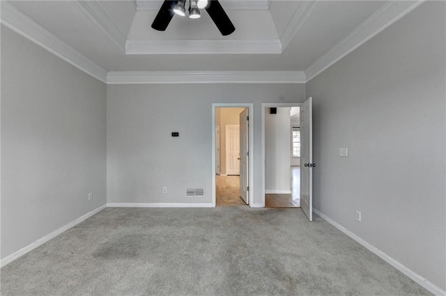 unfurnished bedroom with visible vents, baseboards, ornamental molding, carpet, and a raised ceiling