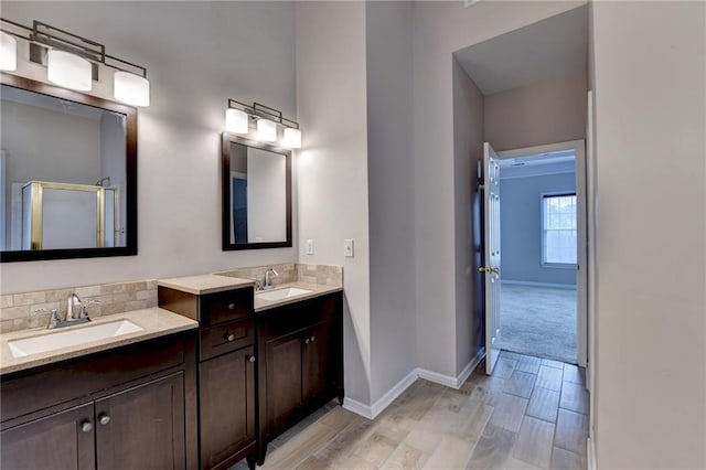 full bathroom featuring a sink, a shower stall, baseboards, and double vanity