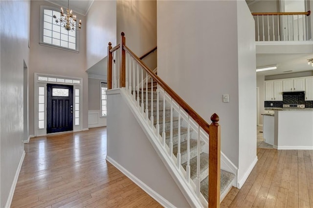 entryway featuring a towering ceiling, light wood-style flooring, and baseboards