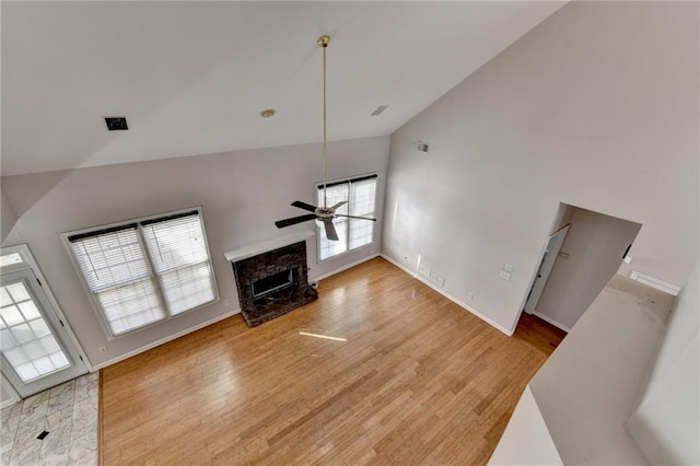 living room featuring light wood-style flooring, a ceiling fan, a high end fireplace, high vaulted ceiling, and baseboards