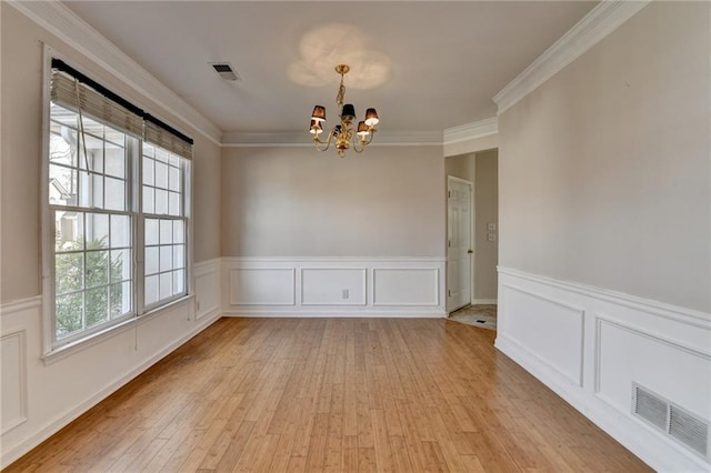 empty room featuring light wood-style floors, visible vents, crown molding, and an inviting chandelier