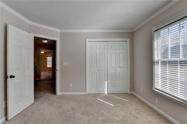 unfurnished bedroom with ornamental molding, a closet, light carpet, and baseboards