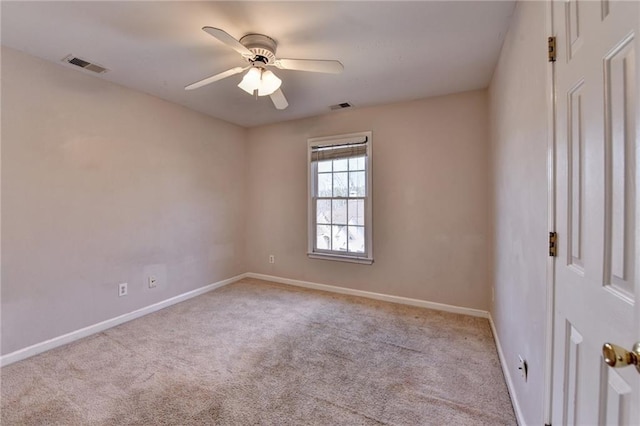 carpeted spare room featuring baseboards, visible vents, and ceiling fan