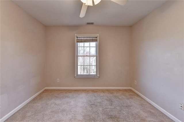 carpeted spare room featuring baseboards, visible vents, and a ceiling fan