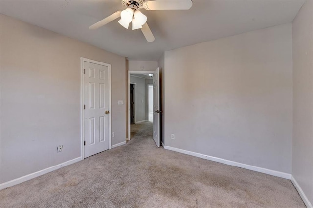 carpeted spare room featuring a ceiling fan and baseboards