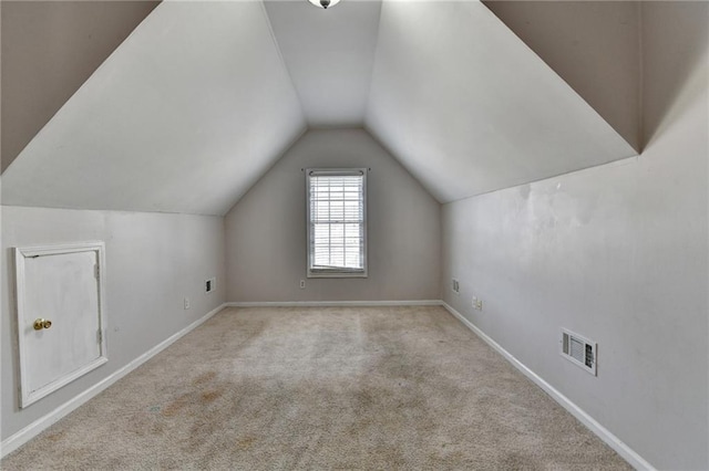 additional living space with baseboards, visible vents, vaulted ceiling, and carpet flooring