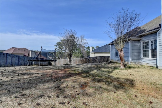 view of yard with a trampoline and a fenced backyard