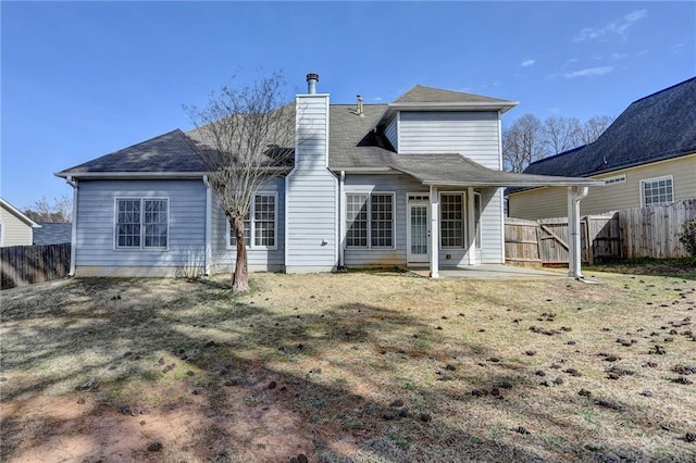 rear view of house with a patio area, a chimney, fence, and a yard