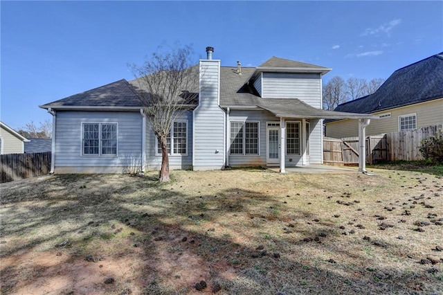 rear view of house featuring a patio area, a chimney, and fence