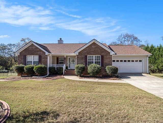 single story home with covered porch, a front yard, and a garage