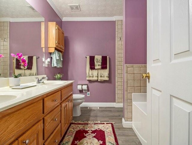 bathroom with a bath, wood-type flooring, a textured ceiling, and ornamental molding