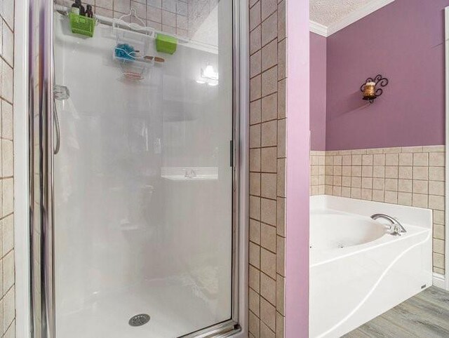 bathroom with separate shower and tub, hardwood / wood-style floors, a textured ceiling, and ornamental molding