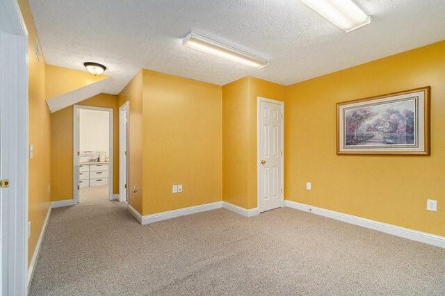 empty room with light carpet and a textured ceiling