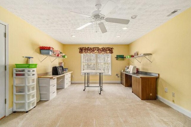 home office featuring light carpet, ceiling fan, and a textured ceiling