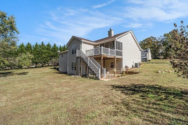 rear view of property with a sunroom, a yard, central AC unit, and a deck