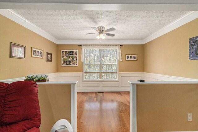 interior space featuring crown molding, light hardwood / wood-style floors, and a textured ceiling