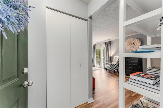 corridor with a textured ceiling and wood finished floors