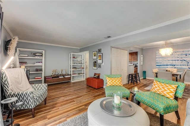 living area with visible vents, wood finished floors, a notable chandelier, and crown molding