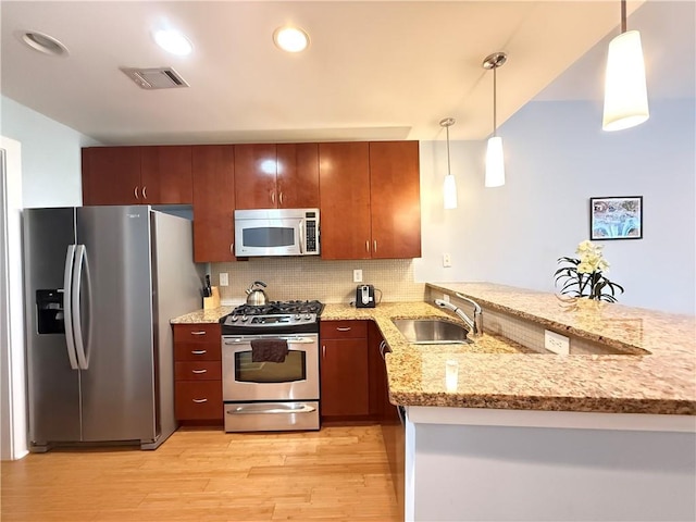 3655 Peachtree Rd NE Unit 304, Atlanta, GA 30319 - kitchen featuring stainless steel appliances, a peninsula, a sink, light wood-style floors, and pendant lighting