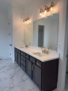 full bath featuring marble finish floor, double vanity, and a sink