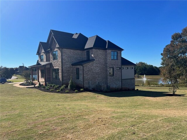 view of side of home featuring stone siding, a water view, and a yard