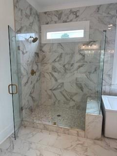 bathroom featuring marble finish floor, a soaking tub, and a marble finish shower