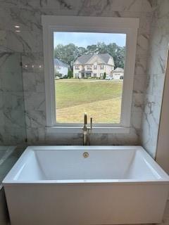 full bathroom with a freestanding tub and plenty of natural light