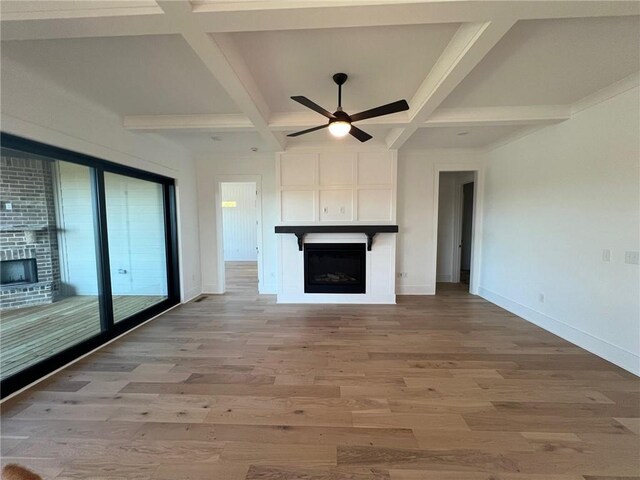 unfurnished living room featuring light wood-type flooring, a large fireplace, and coffered ceiling