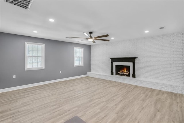 unfurnished living room with light wood-type flooring, a brick fireplace, baseboards, and visible vents