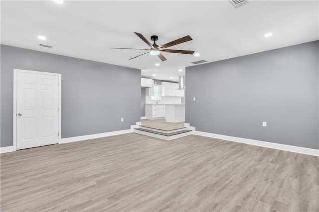 unfurnished living room with light wood-style floors, ceiling fan, visible vents, and baseboards