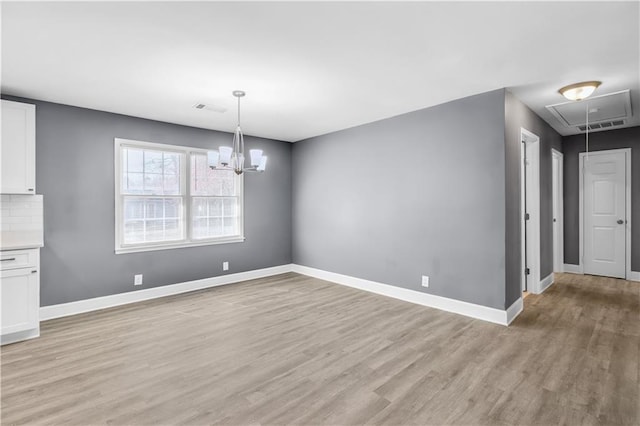 unfurnished dining area featuring visible vents, light wood finished floors, attic access, and baseboards