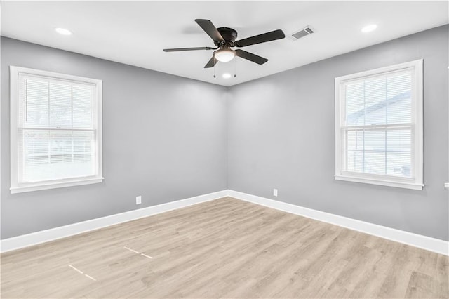 spare room featuring light wood finished floors, visible vents, and baseboards