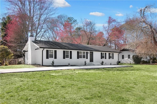 rear view of house with a yard, a chimney, and fence