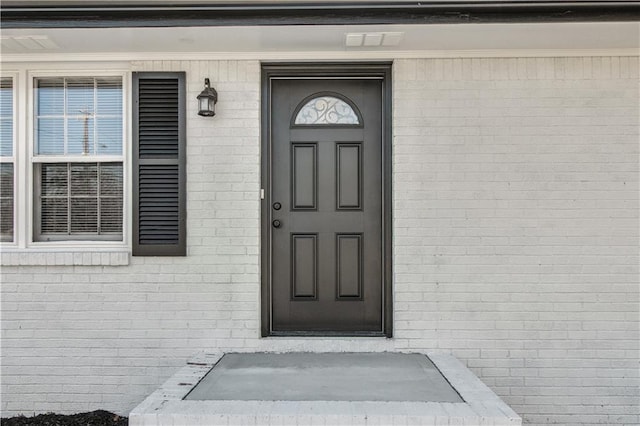 view of exterior entry featuring brick siding