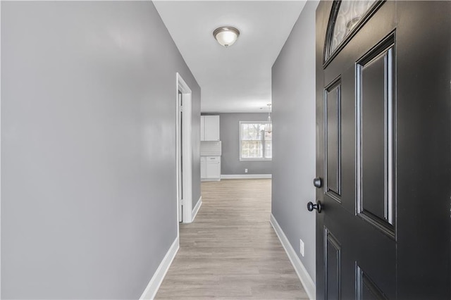 hall with baseboards and light wood finished floors