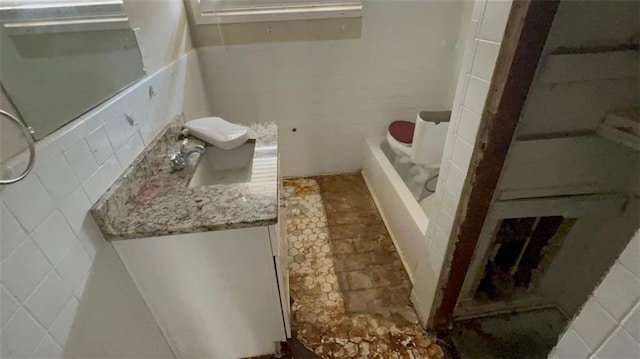 bathroom featuring vanity, tile walls, and a bathing tub