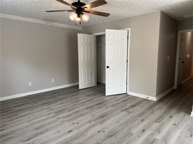 7454 Woody Springs Dr, Flowery Branch, GA 30542 - unfurnished bedroom with baseboards, wood finished floors, a textured ceiling, a closet, and a ceiling fan