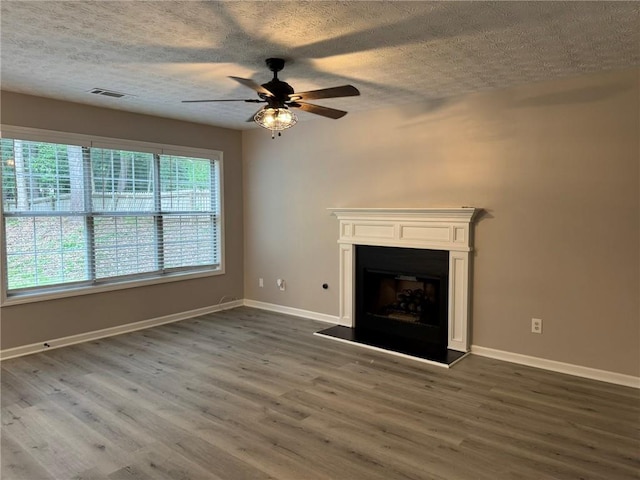 7454 Woody Springs Dr, Flowery Branch, GA 30542 - unfurnished living room featuring ceiling fan, dark wood-type flooring, baseboards, a fireplace with raised hearth, and a textured ceiling