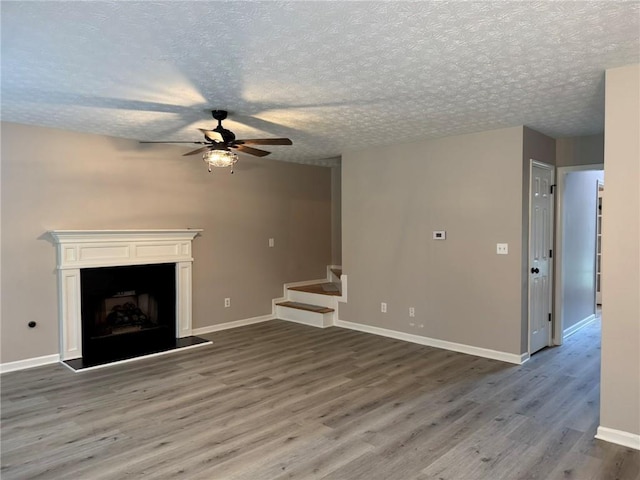 7454 Woody Springs Dr, Flowery Branch, GA 30542 - unfurnished living room with ceiling fan, stairs, wood finished floors, baseboards, and a textured ceiling