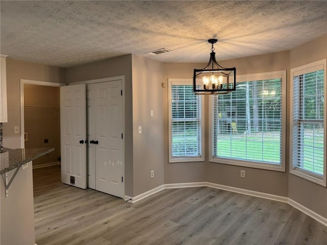 7454 Woody Springs Dr, Flowery Branch, GA 30542 - unfurnished dining area featuring light wood finished floors, a chandelier, a textured ceiling, and baseboards