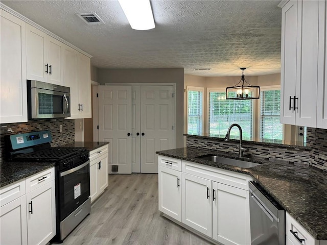 7454 Woody Springs Dr, Flowery Branch, GA 30542 - kitchen with stainless steel appliances, a sink, a textured ceiling, a peninsula, and white cabinets